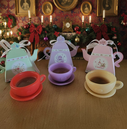 Miniature tea set with colorful teacups and saucers on a wooden surface, with decorative background.
