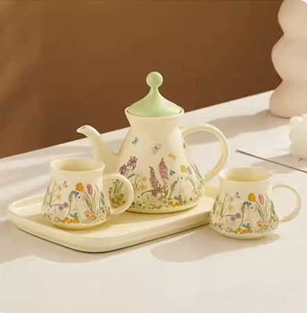 Ceramic tea set with teapot, cups, and tray featuring animal and floral designs on a light surface.