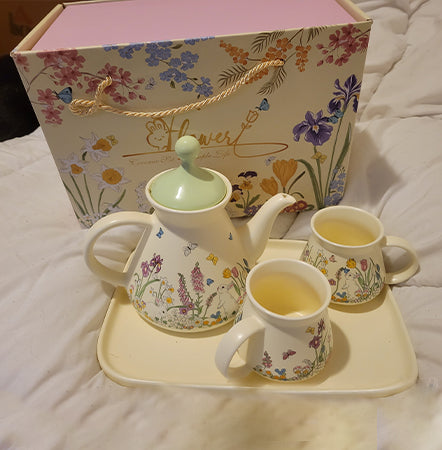 Floral teapot and mugs set with matching box on a white surface