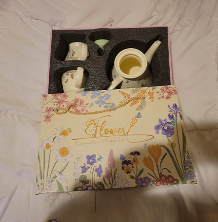 Tea set with floral packaging on a plain background