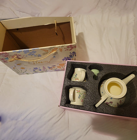 Set of ceramic tea cups and saucers in a decorative box with floral design.