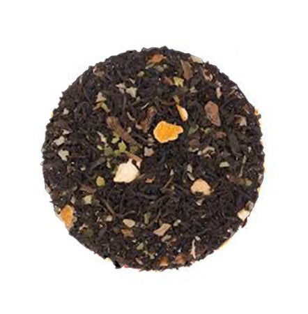 Tea ball with black tea leaves and visible herbs on a white background