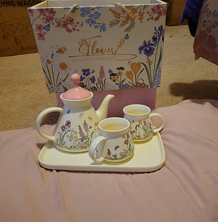 Floral teapot and mugs set with matching carrying case on a table.