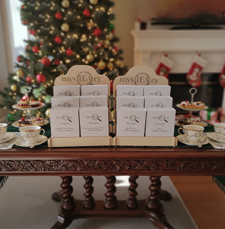 Tea boxes on a wooden table with a Christmas tree in the background